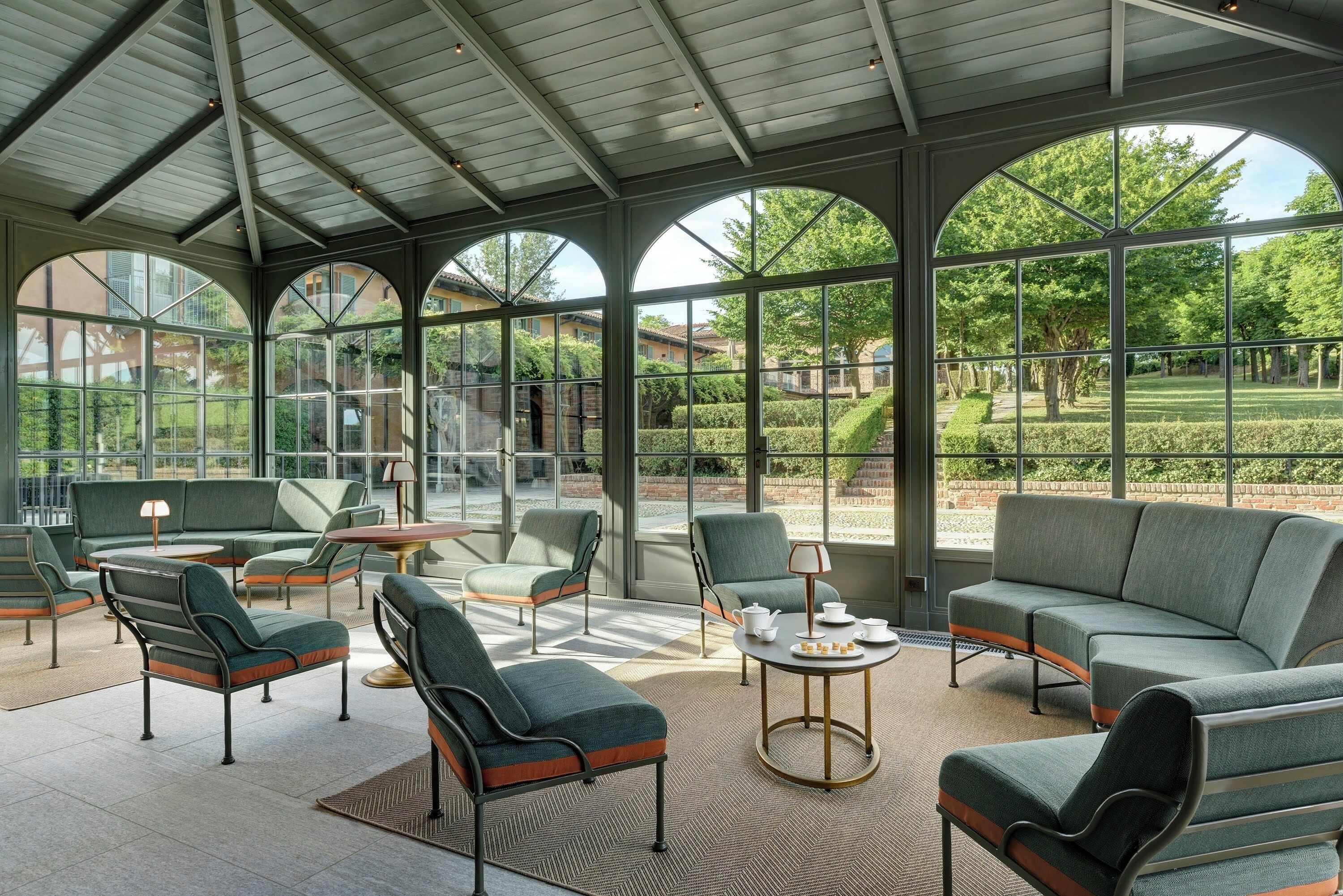 A spacious covered patio with modern furniture and large windows offering views of the surrounding landscape.