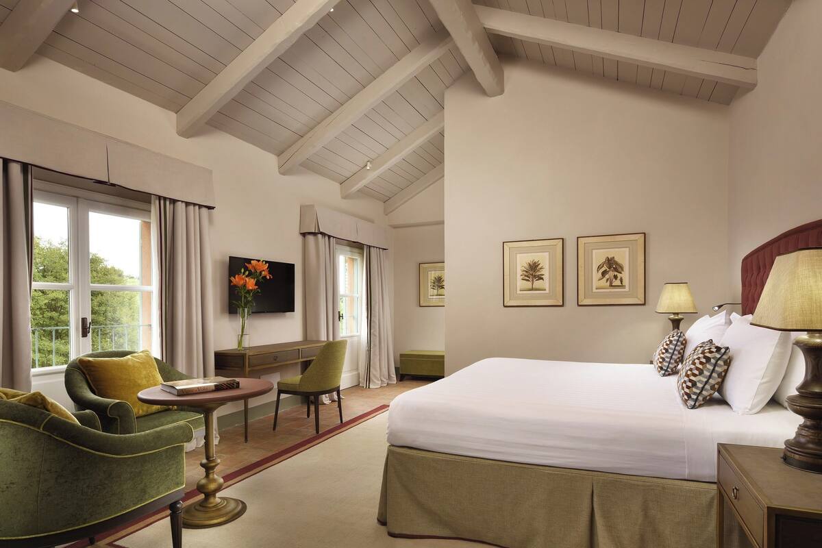Une chambre d’hôtel avec un lit, un bureau, une chaise et un téléviseur.