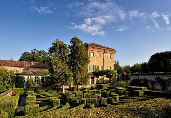 A large building with a garden maze, a brick facade, and a clear blue sky.