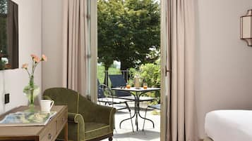 Een kamer met een bed, een stoel, een tafel met een karaf en glazen, en uitzicht op het omliggende landschap.