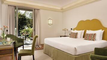 A hotel room with a bed, a chair, a table with a vase and a cup, and a view of the outdoors.