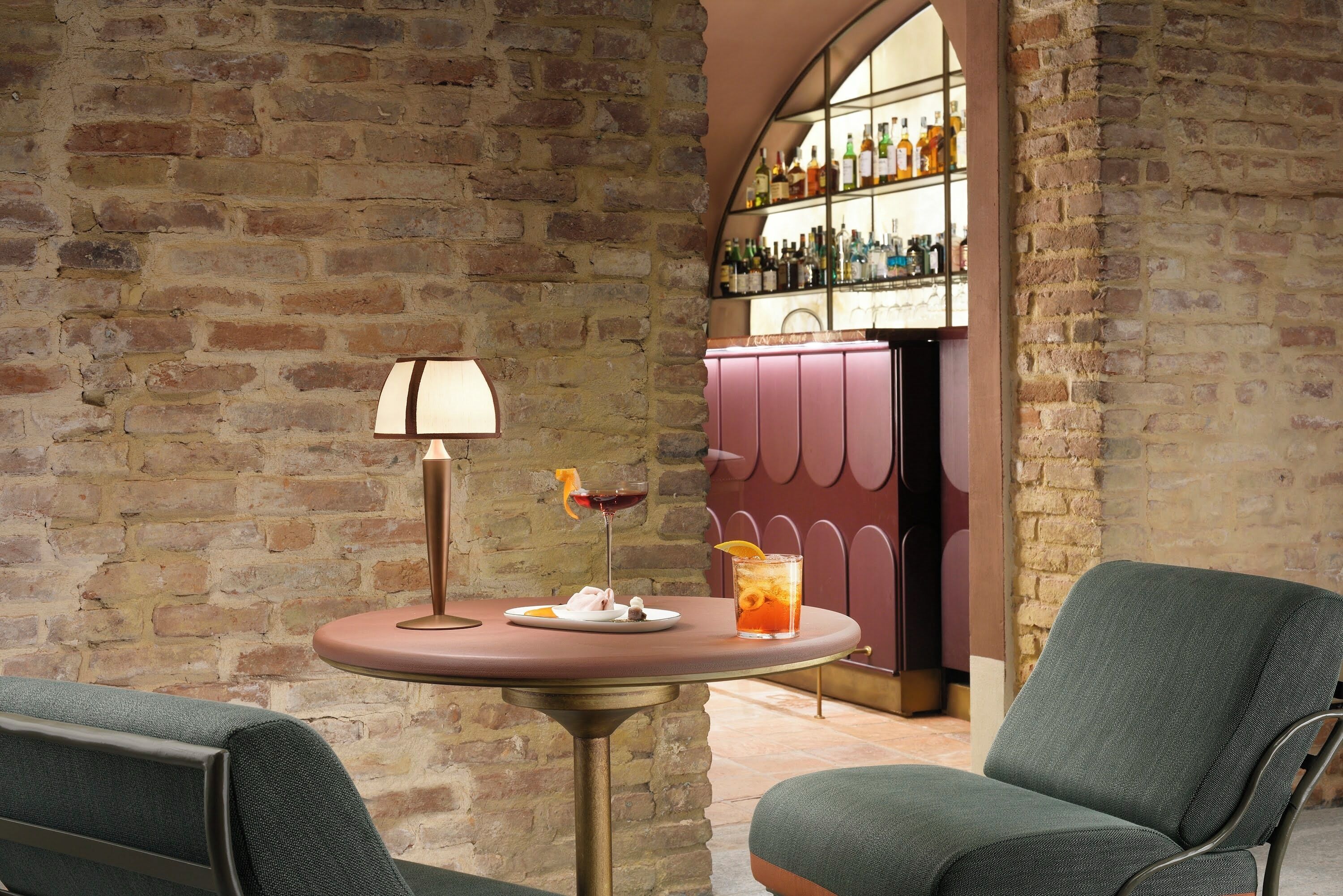 Eine gemütliche Sitzecke mit einem Tisch, einer Lampe und einer Bar mit Regalen voller Flaschen.