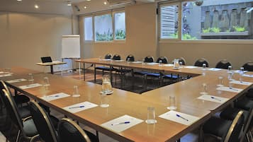 Une salle de conférence avec une longue table, des chaises, un ordinateur portable et un tableau blanc.