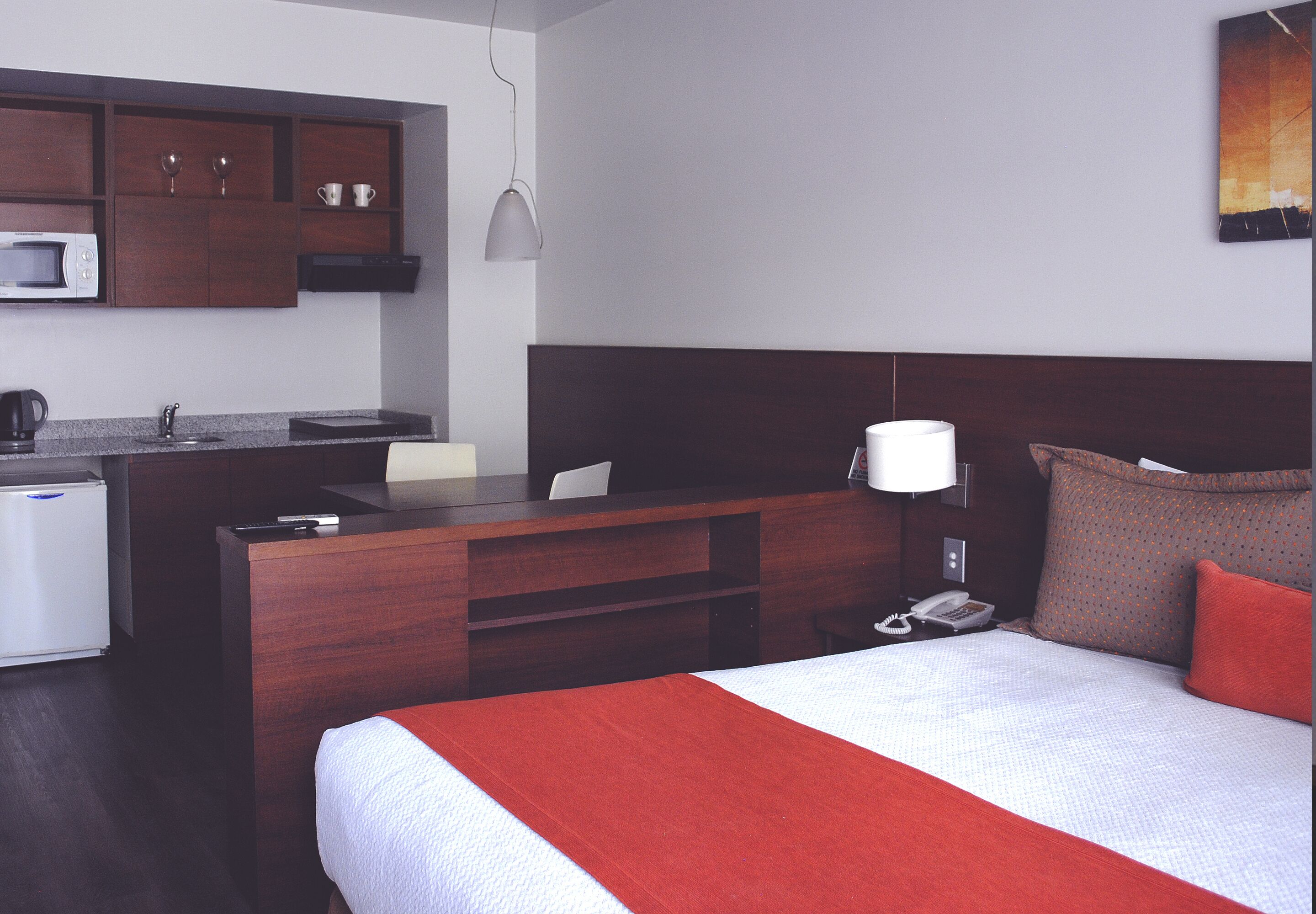 A hotel room with a bed, a desk, a microwave, a coffee maker, and a telephone.