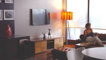 A living room with a sofa, a coffee table, a TV mounted on the wall, and a floor lamp.