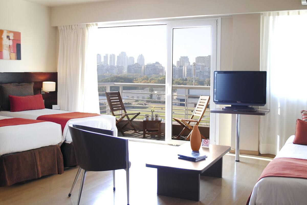 Een hotelkamer met twee bedden, een televisie, een tafel en een stoel.