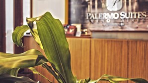 Een receptiebalie met een bord voor Palermo Suites, een klok en een plant.