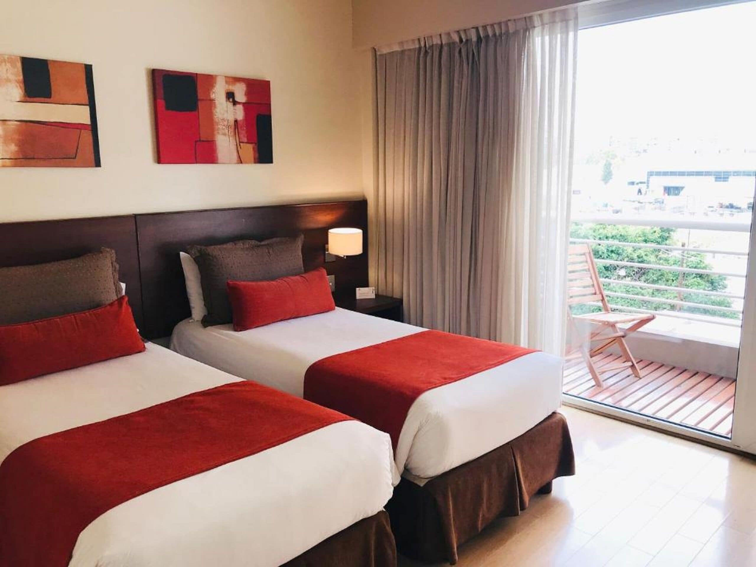 Une chambre d’hôtel avec deux lits, un balcon et des œuvres d’art accrochées au mur.