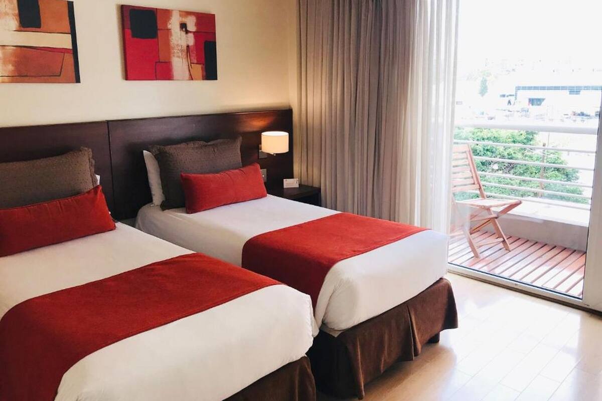 Een hotelkamer met twee bedden, een balkon en kunst aan de muur.