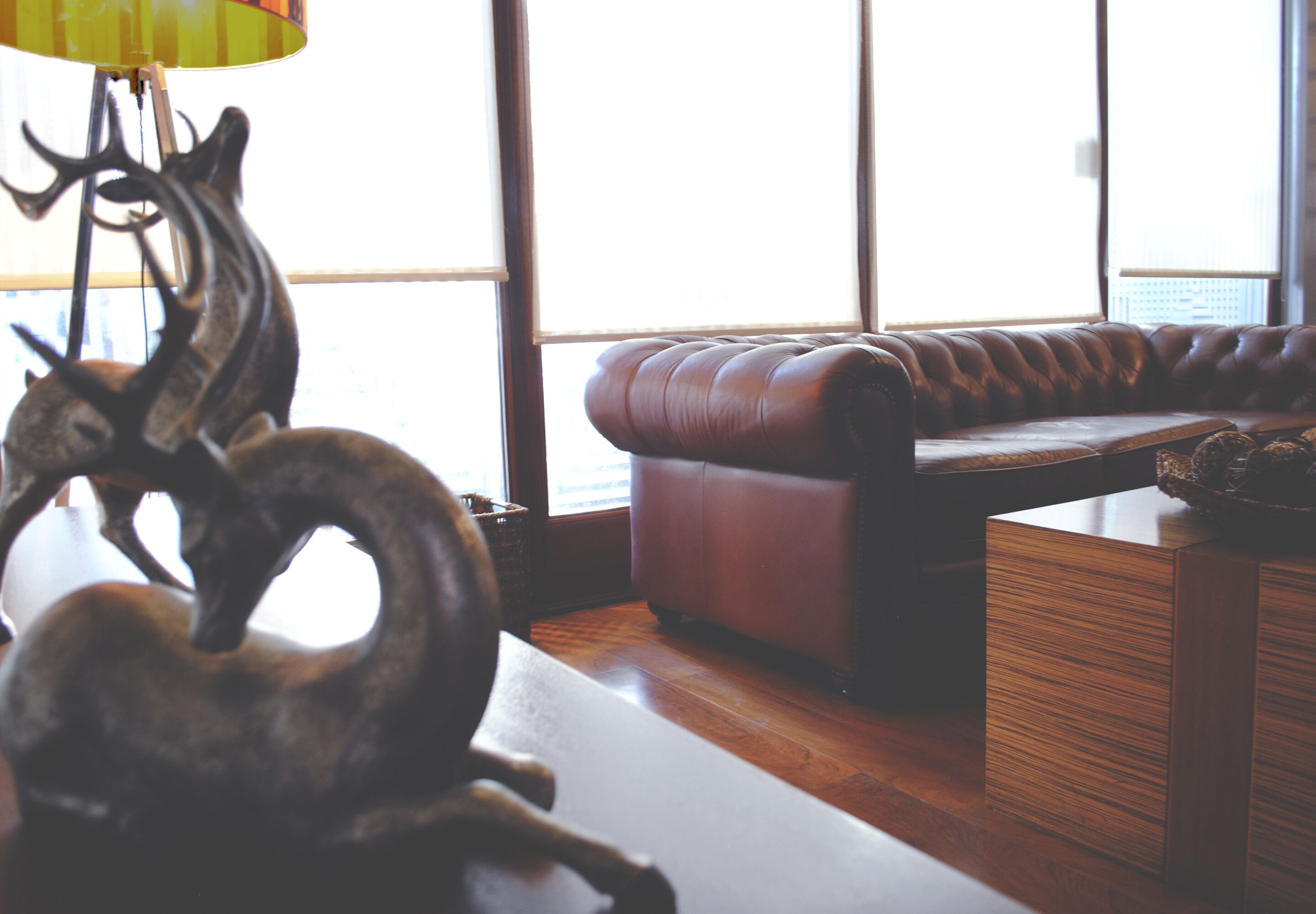 A room with a leather sofa, a wooden coffee table, and a decorative metal sculpture.