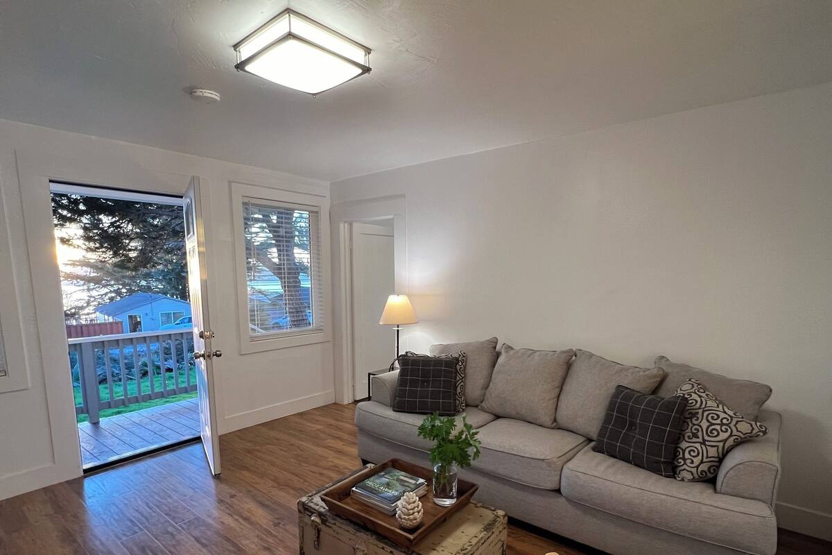 A living room with a grey sofa, a striped armchair, a vintage suitcase coffee table, and a lamp.