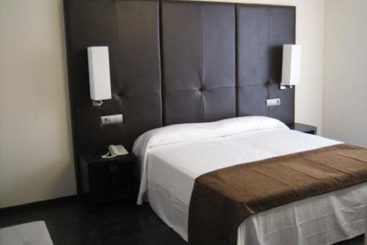 Ein Hotelzimmer mit einem großen Bett, einem Nachttisch und zwei Wandlampen.