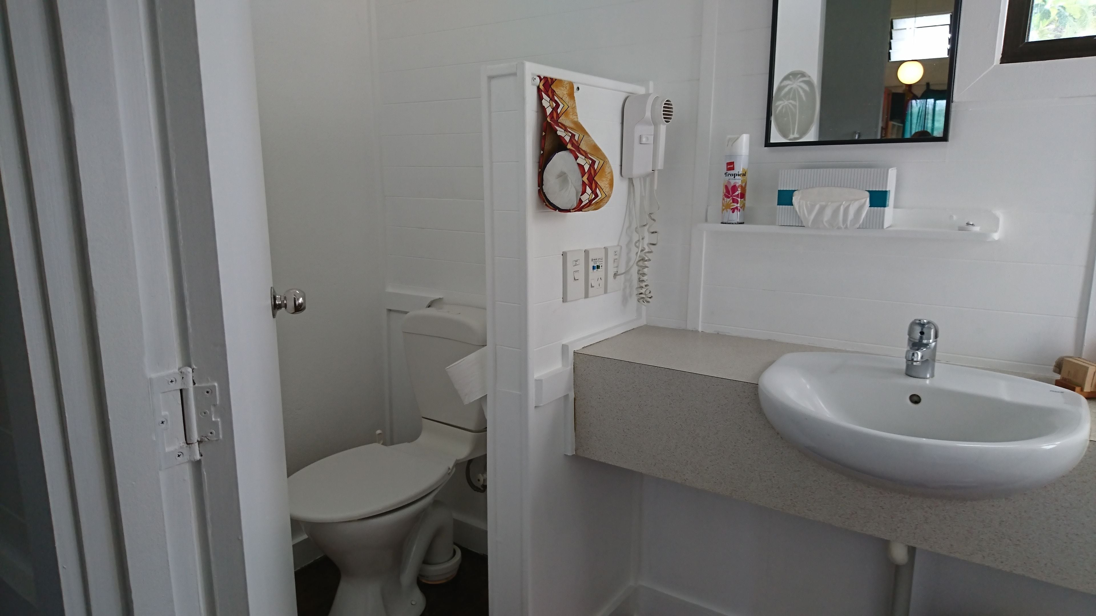 A small, clean bathroom with a toilet, sink, and a towel rack.