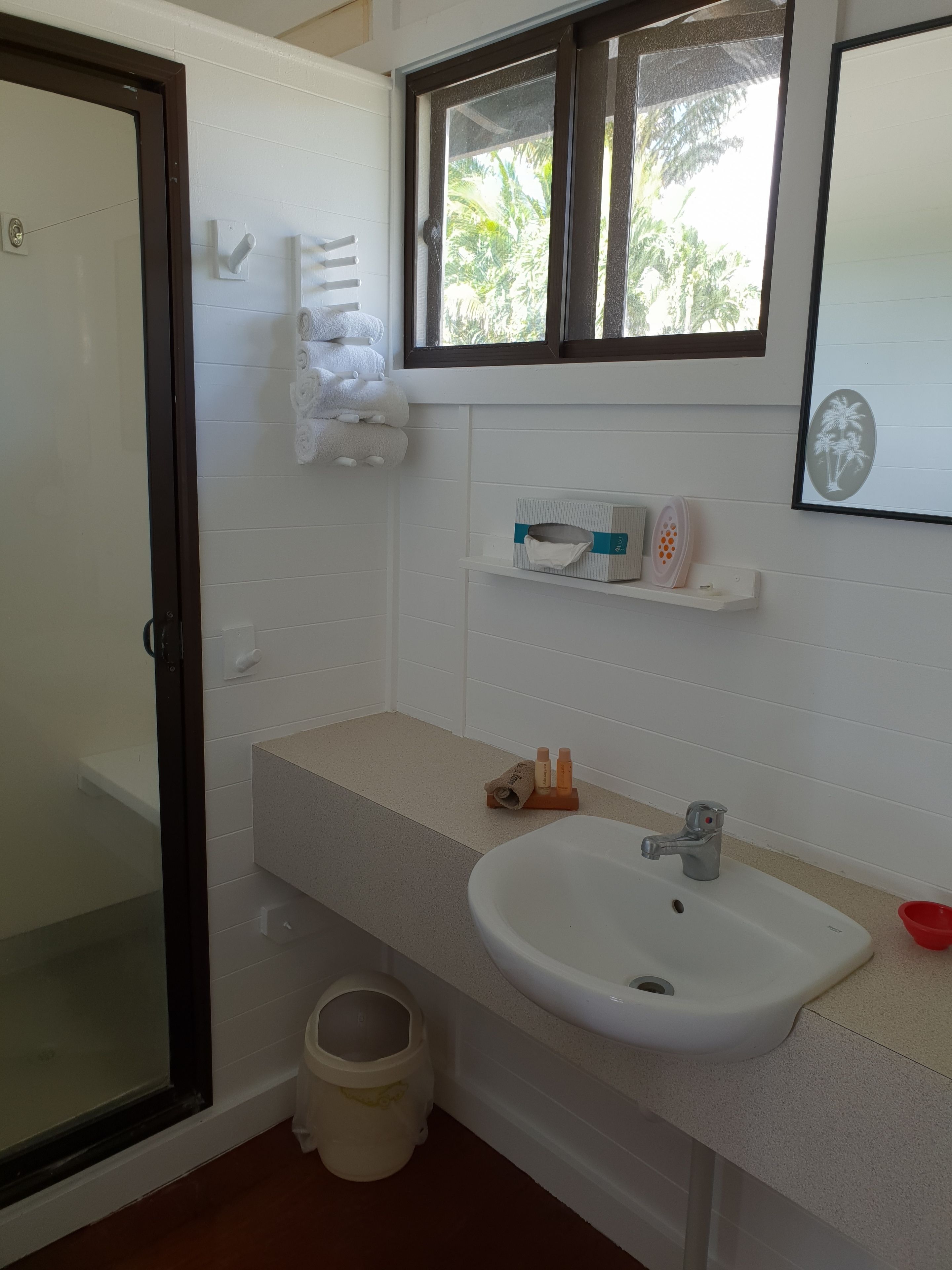 A bathroom with a white sink, a mirror, a towel rack, and a shower area.