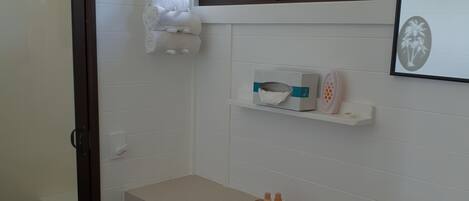 A bathroom with a white sink, a mirror, a towel rack, and a shower area.