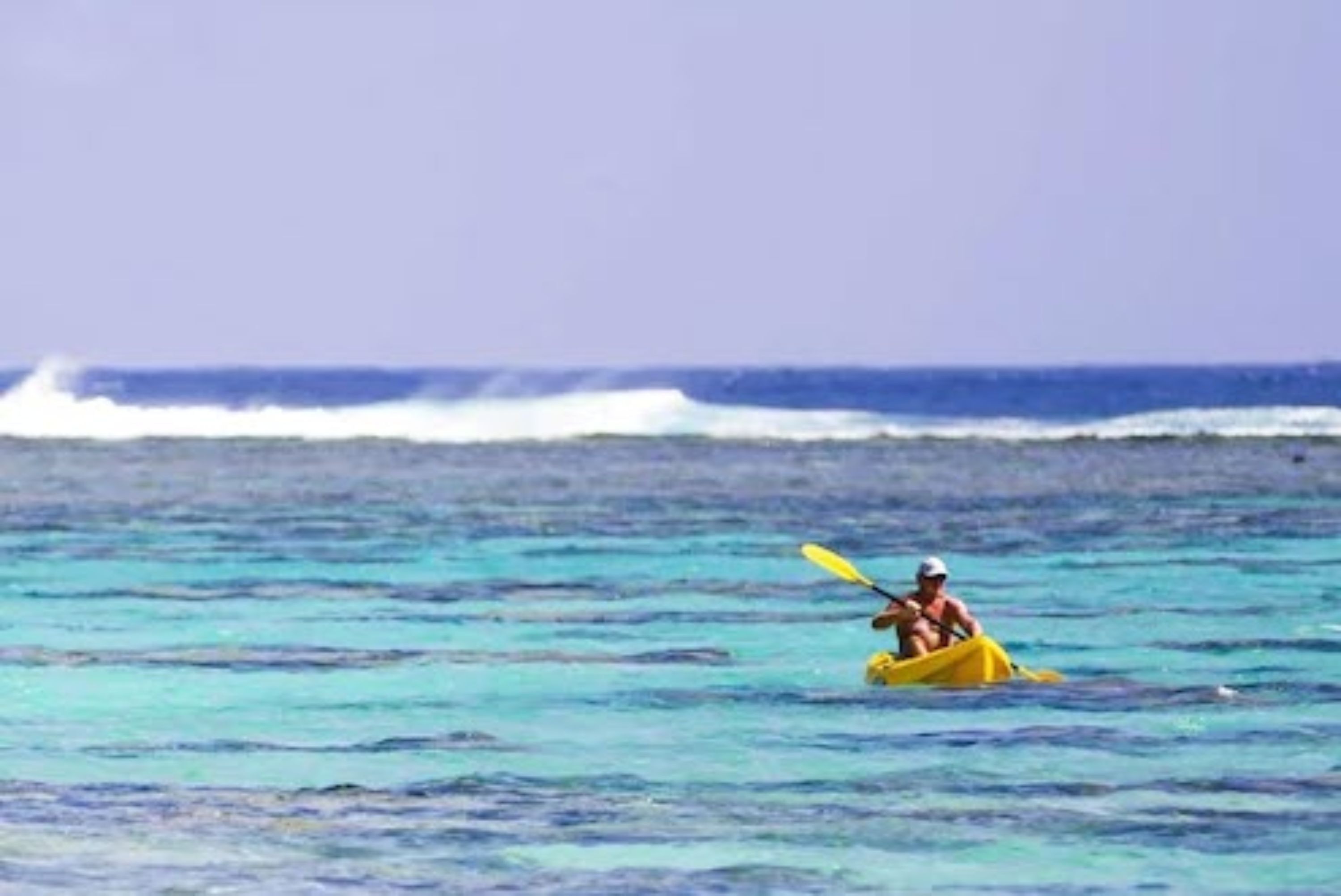 Une personne fait du kayak sur une mer calme, à bord d’un kayak jaune.