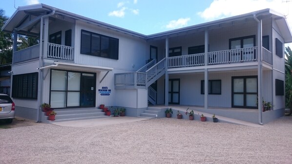 A two-story building with a reception area, multiple balconies, and potted plants.
