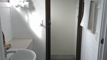 Un baño pequeño con lavamanos blanco, inodoro y zona de ducha.