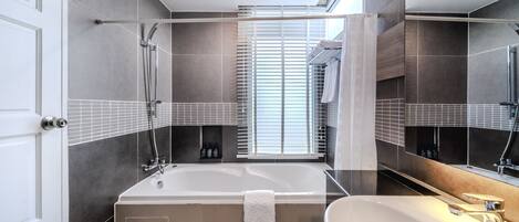 Un baño moderno con una bañera grande, un lavamanos y un espejo.