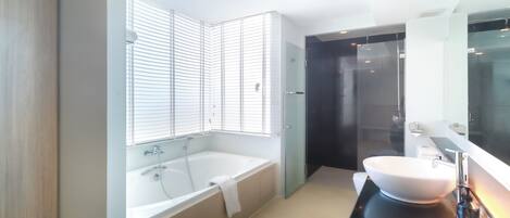 A modern bathroom with a freestanding bathtub, a large mirror, and a glass shower enclosure.