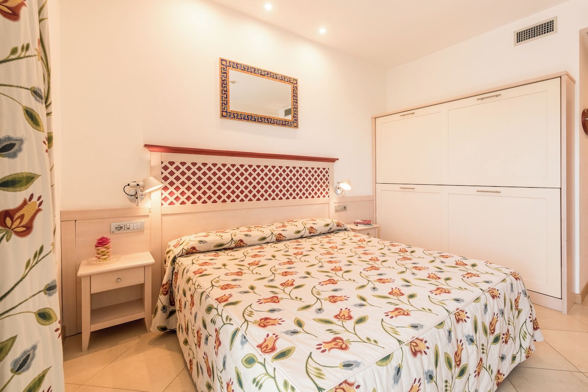 A bedroom with a bed, bedside tables, a wardrobe, and a mirror.