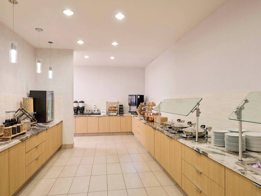 Una cocina moderna con armarios de madera, encimera de mármol y vitrina de vidrio.
