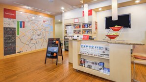 A hotel reception area with a map, a coffee machine, a fruit bowl, and a TV.
