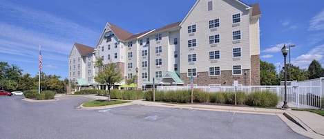 A multi-story hotel with a central courtyard, a flagpole, and a gated entrance.