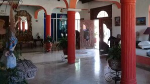 A spacious lobby with high ceilings, red columns, and a chandelier.