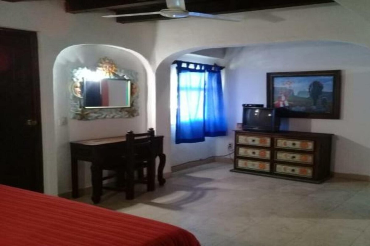 A room with a bed, a desk, a dresser, a mirror, and a television.