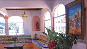 A room with a colorful sofa set, a table, and a large potted plant.