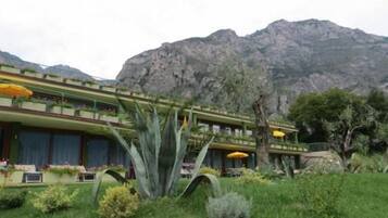 A hotel with a green and yellow facade, multiple balconies, and a mountainous backdrop.