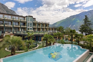 A hotel with a pool, balconies, and a mountainous backdrop. - Hotel Alexander (Limone sul Garda)