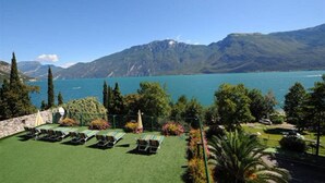 Un espace piscine avec des chaises longues et une vue sur un lac et des montagnes.