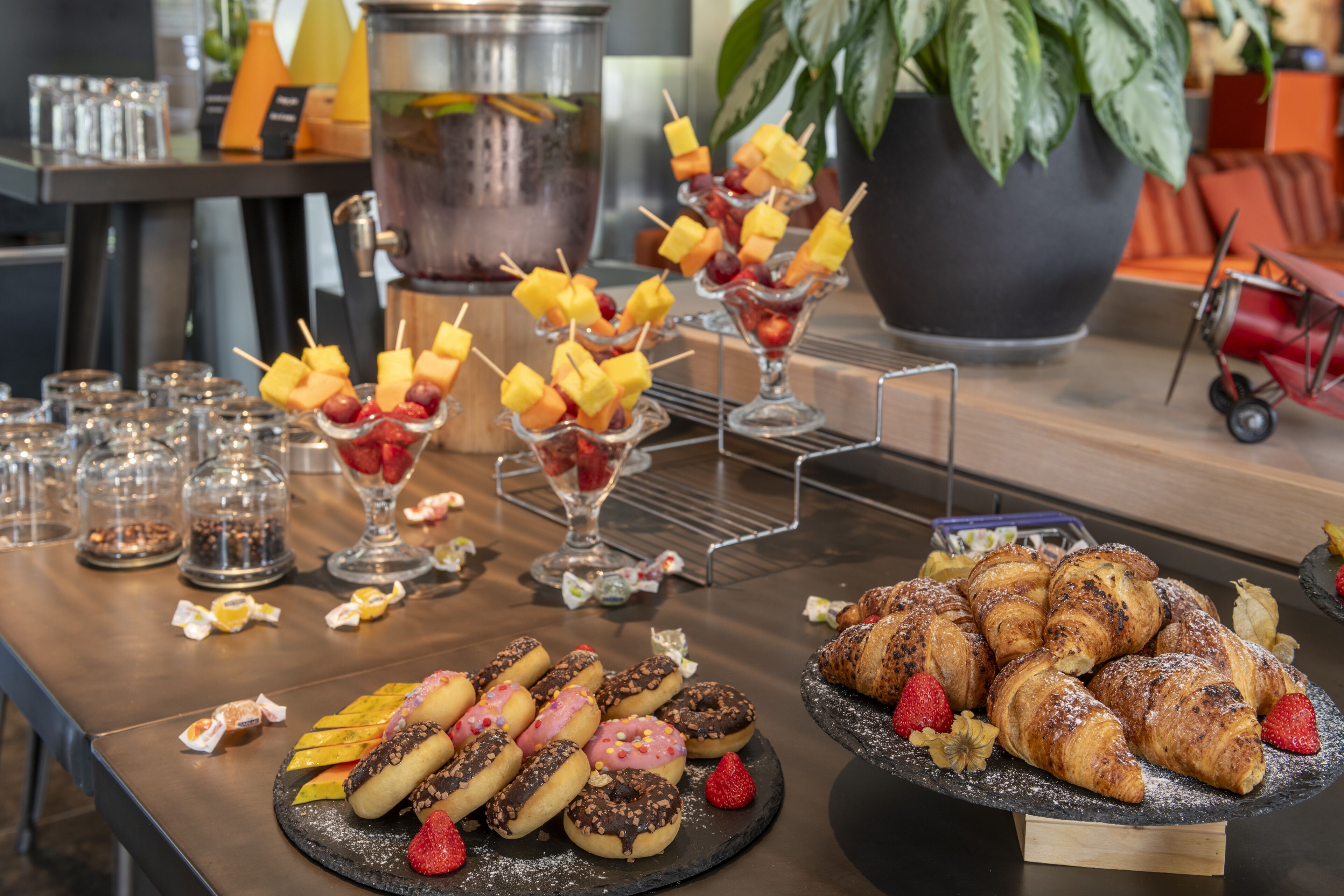 A buffet table with various food items including pastries, fruit skewers, and desserts.