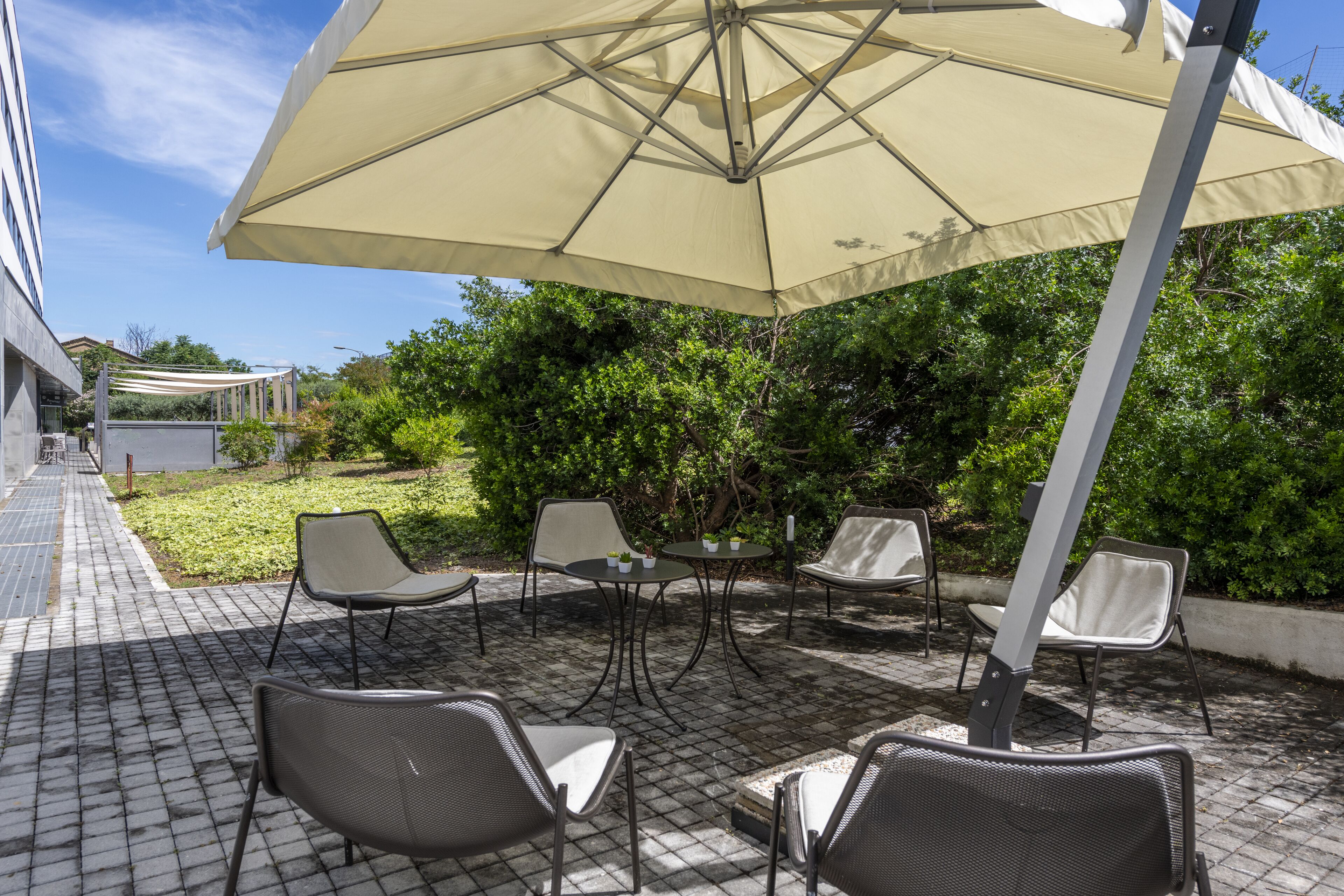 An outdoor patio with a large umbrella, several chairs, and a table.