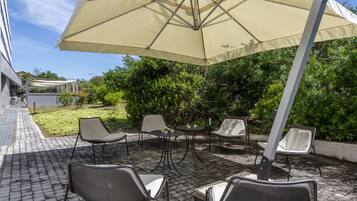 An outdoor patio with a large umbrella, several chairs, and a table.