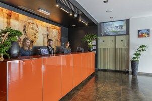 Una reception con tre membri dello staff, un grande murale e uno schermo digitale che mostra una veduta cittadina.