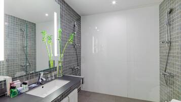 Une salle de bain moderne avec un grand miroir, deux lavabos, une douche et des toilettes.