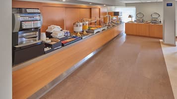 A hotel breakfast area with a self-service coffee machine, a variety of food options, and a clean, modern design.