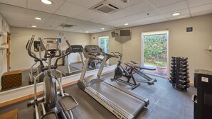 Un gimnasio con cintas de correr, elípticas y una bicicleta estática.