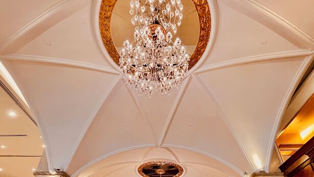 Un vaste hall d’entrée avec un plafond haut, de magnifiques lustres et un sol en marbre poli.