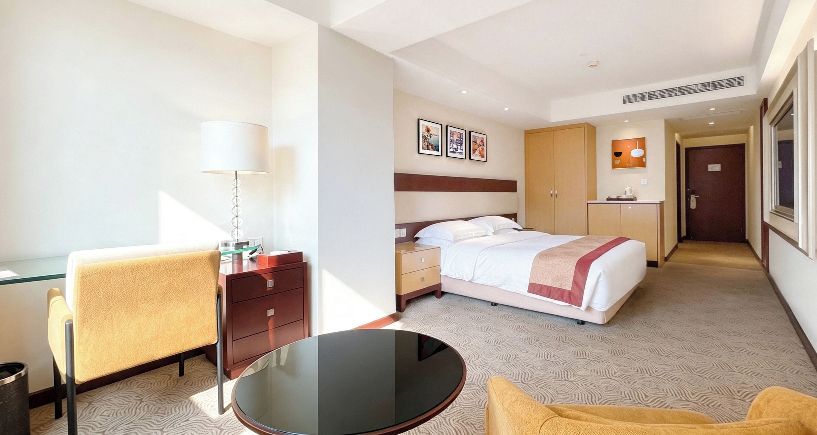 A hotel room with a bed, bedside table, lamp, chair, and a small table.