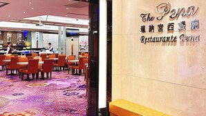 L’intérieur d’un restaurant, avec des tables et des chaises, un tapis à motifs et un mur sur lequel est inscrit le nom du restaurant.