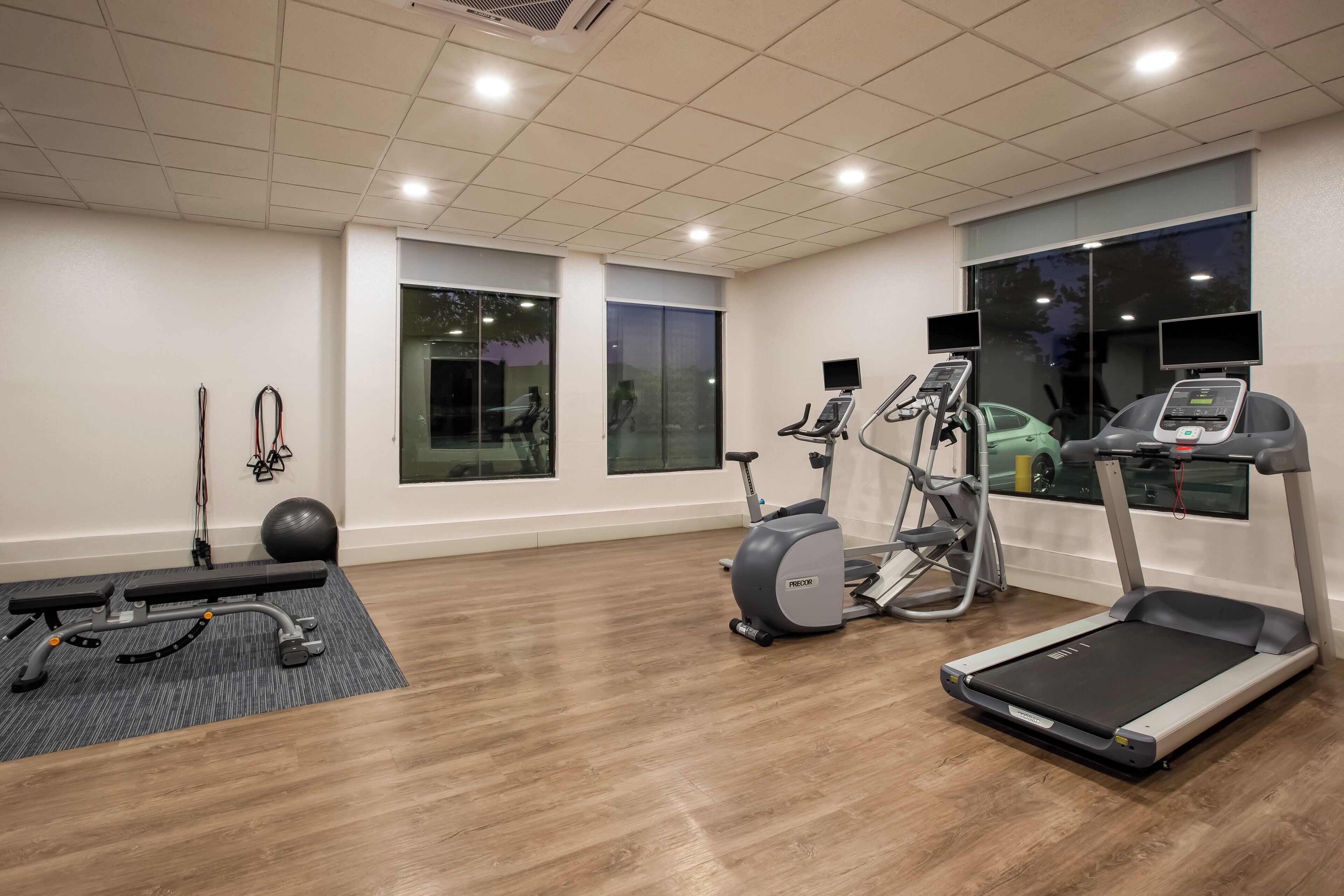 A gym with treadmills, elliptical machines, and exercise balls.