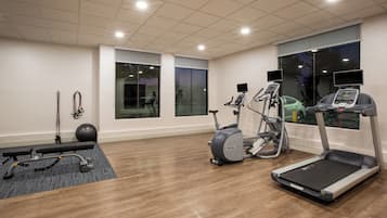 A gym with treadmills, elliptical machines, and exercise balls.