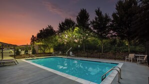 Ein rechteckiger Schwimmteich mit einer Metallleiter und einer gefliesten Poolterrasse rundherum.