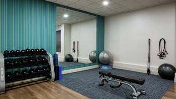 Un gimnasio con equipo de ejercicio, un espejo y una pared azul a rayas.