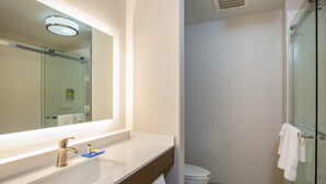 A modern bathroom with a glass shower enclosure, a white sink with a gold faucet, and a large mirror above the sink. - Holiday Inn Express Hotel & Suites Fairburn by IHG (Fairburn)