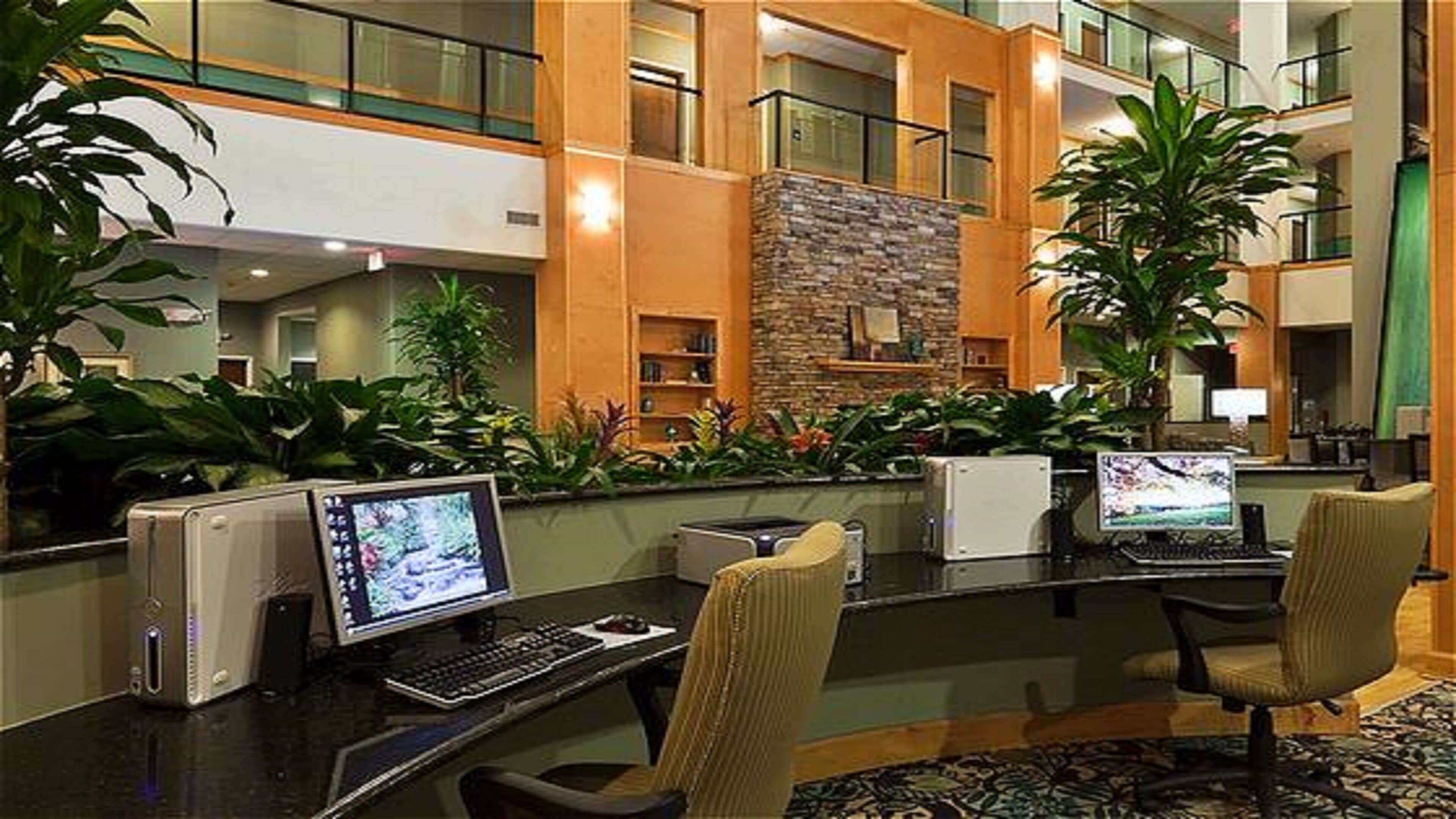 A reception area with multiple computer stations, a stone accent wall, and indoor plants.
